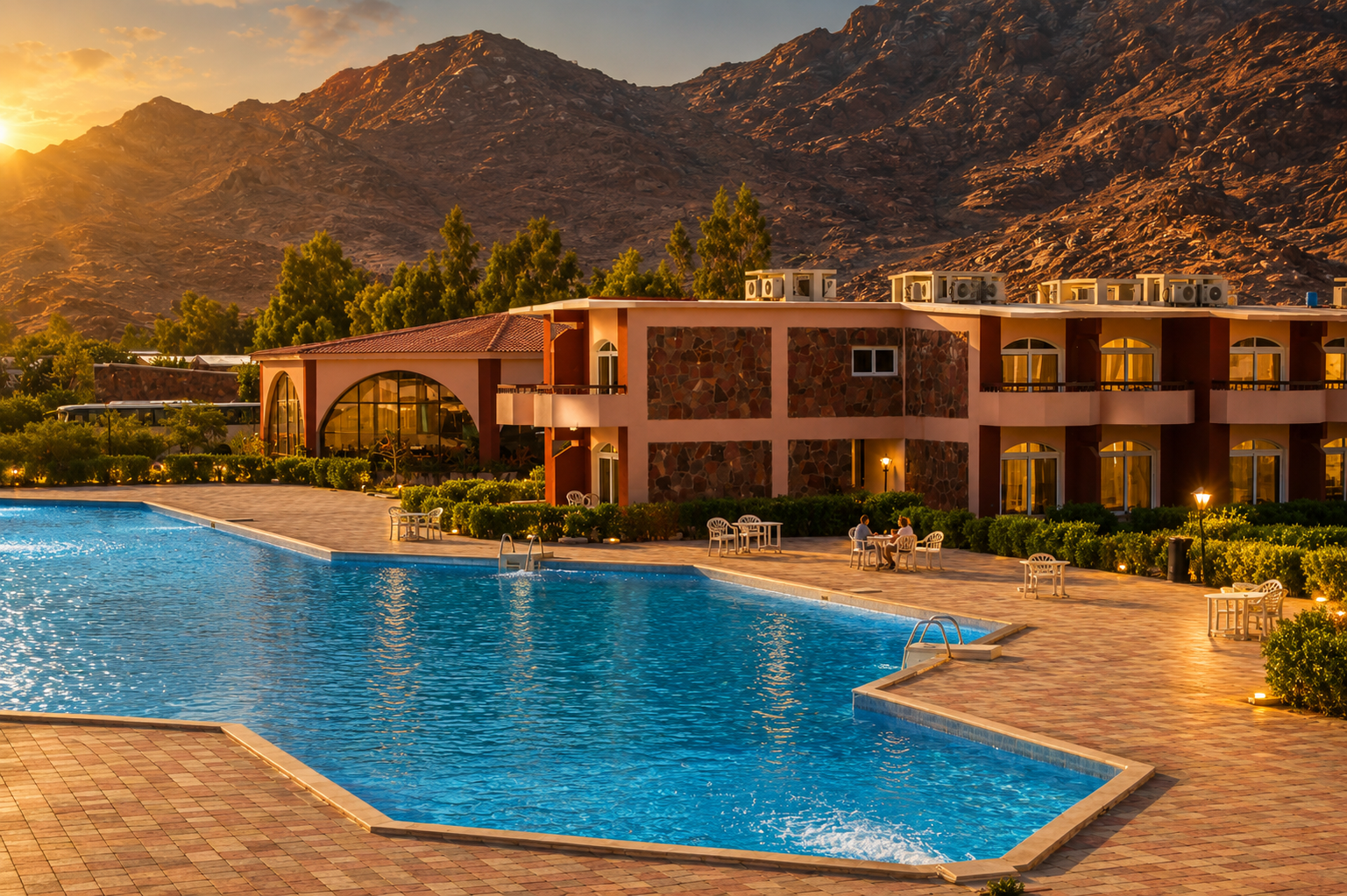 Morgenland Village pool and hotel buildings at sunset with mountain backdrop