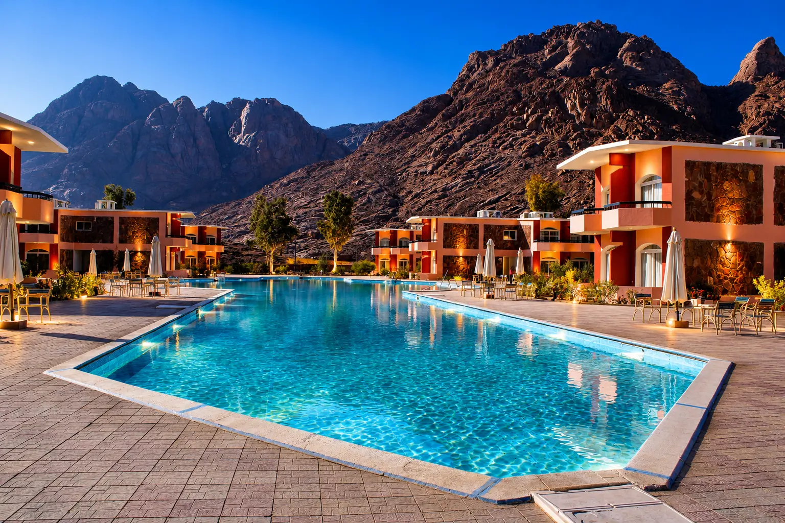 Main pool at dusk framed by mountain-view guest buildings
