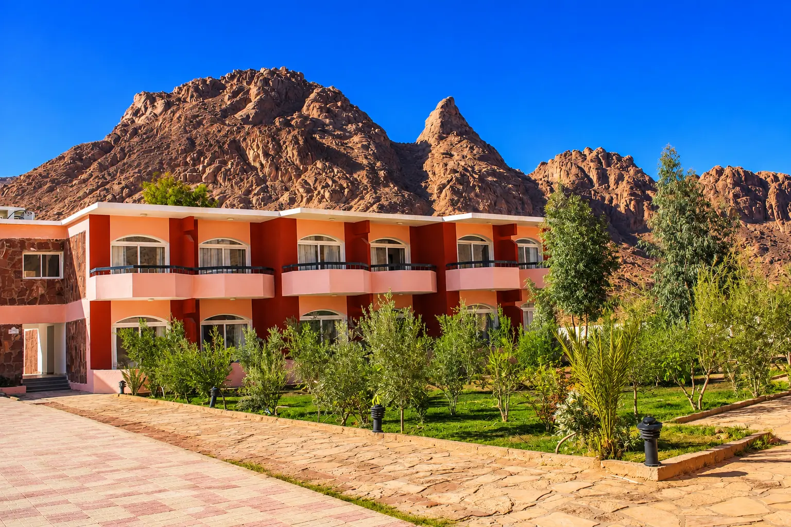 Guest building with balconies and gardens beneath the red Sinai peaks